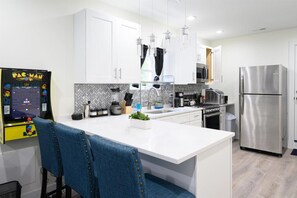 A modern kitchen with white cabinetry, stainless steel appliances, and a central island. - Luxurious, Cozy Beauty 10 min from Downtown Chicago (Chicago)