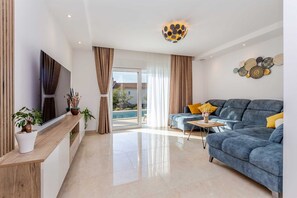 A modern living room with a sofa, a TV, and a dining table. - Holiday house VILLA ANDRO (Pinezići)
