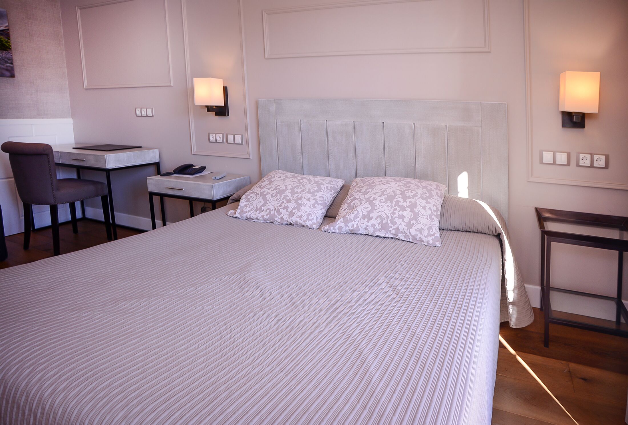 A hotel room with a large bed, a desk, and a chair.