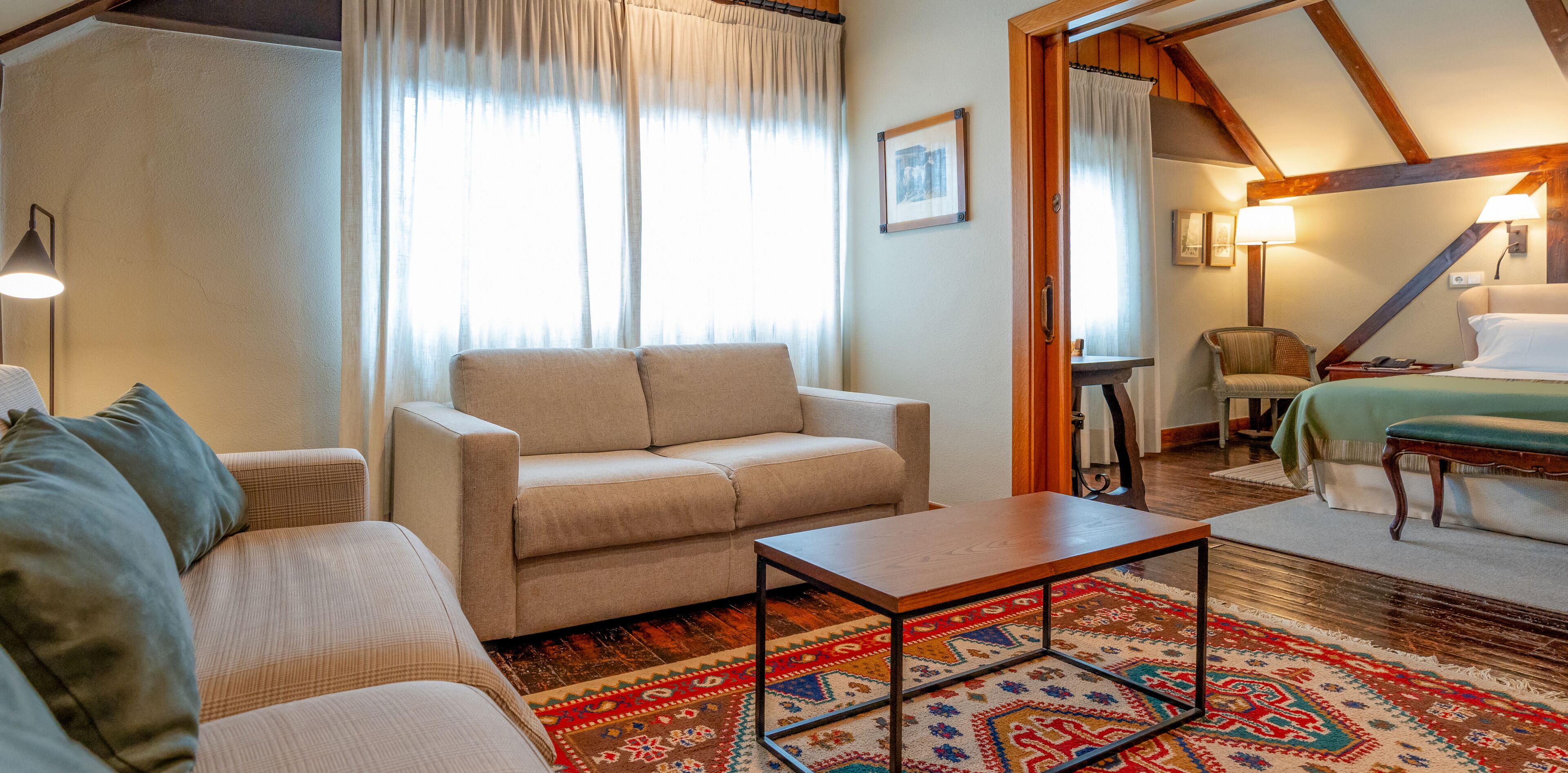 Una habitación acogedora con un sofá, una mesita y una cama con colcha verde.