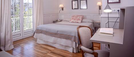 Un dormitorio con una cama grande, un escritorio con lámpara y vistas al exterior a través de una puerta corredera.