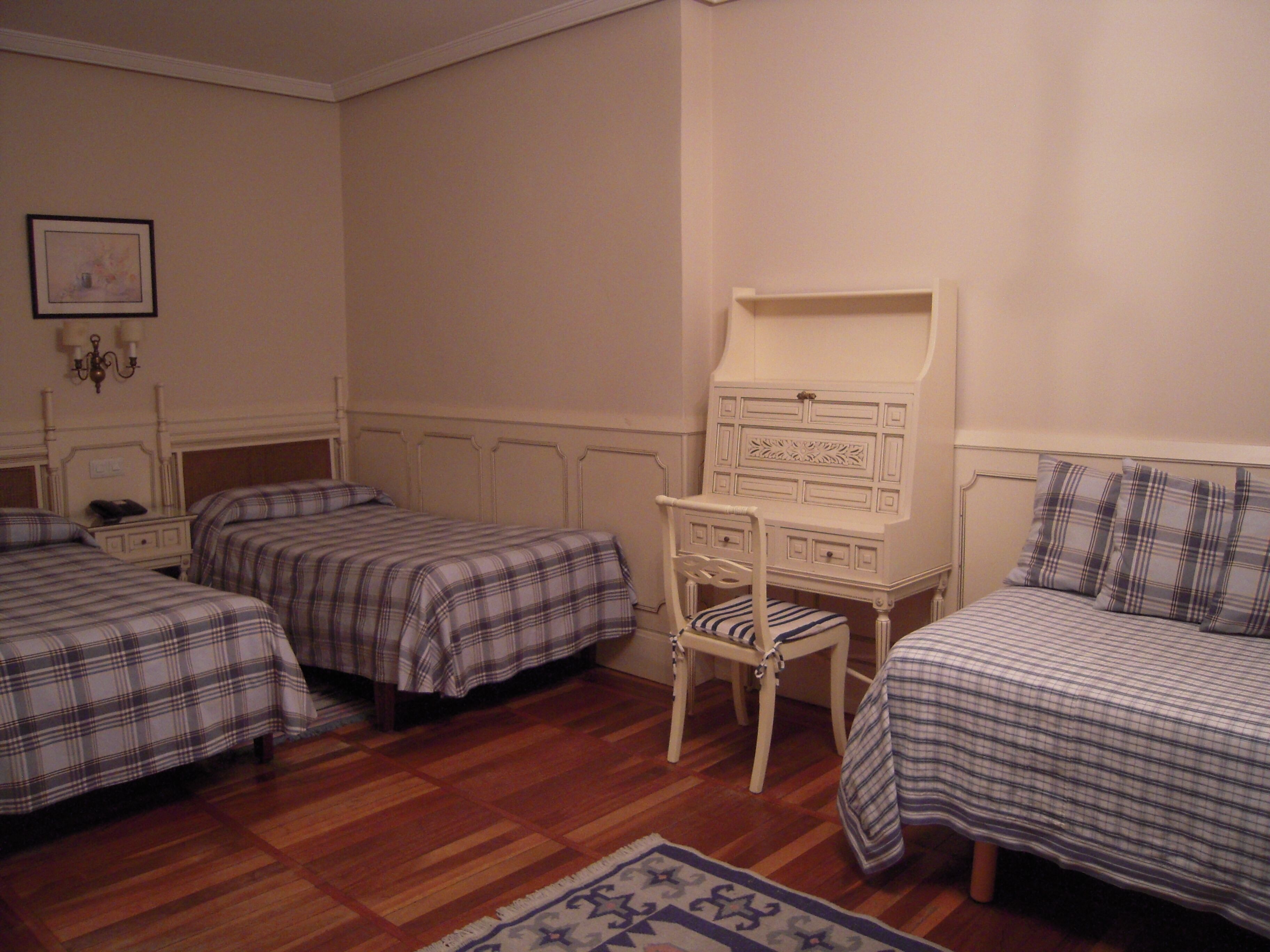 Ein Schlafzimmer mit zwei Betten, einem Schminktisch, einem Stuhl und einem Teppich.