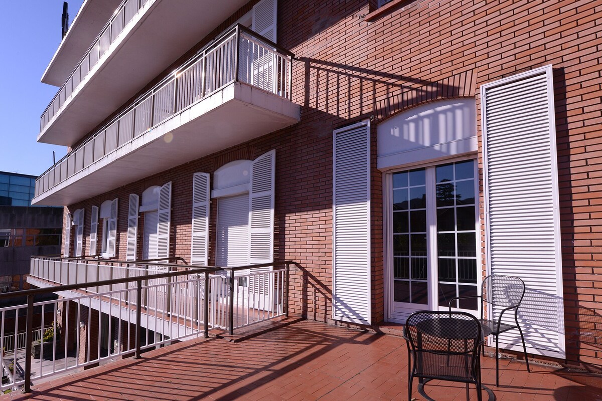 Een meerlaags gebouw met een bakstenen gevel, witte luiken en een balkon met metalen hekwerk.