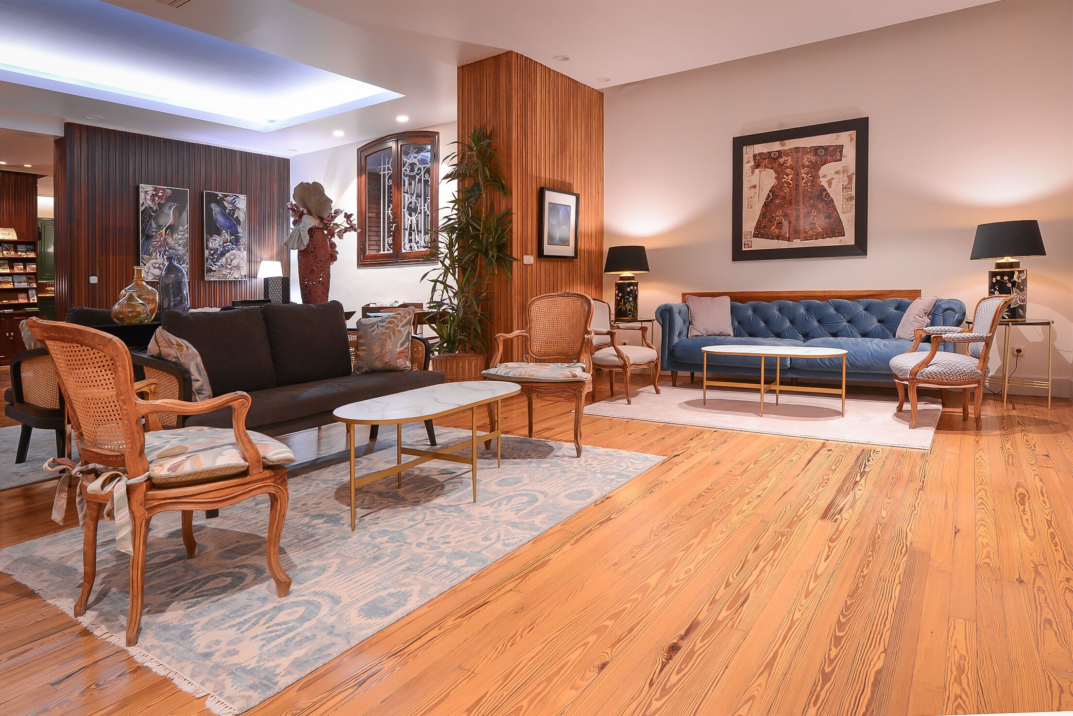 A modern living room with a blue sofa, wooden flooring, and various decorative items.