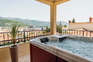 A hot tub on a balcony with a view of a city and mountains. - Studio apartment with big terrace & sea view (Budva)