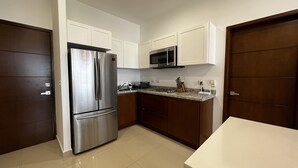A modern kitchen with stainless steel appliances, white cabinets, and a granite countertop. - Ferrara Apartments (Mazatlán)