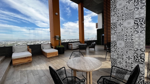 A rooftop terrace with a city view, furnished with a sofa, chairs, and a table. - Ferrara Apartments (Mazatlán)