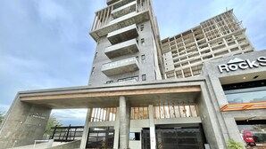 A modern building with a prominent entrance, a sign for 'RockS', and a landscaped area with plants. - Ferrara Apartments (Mazatlán)