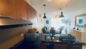 Una cocina moderna con armarios de madera, horno empotrado y comedor con mesa y sillas.