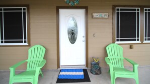 A front door with a welcome sign, two green chairs, and a mat. - Welcome to Casa del Mar! Less than a mile away from beach! (Port Aransas)
