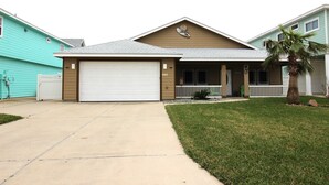 A residential house with a garage, a front porch, and a lawn. - Welcome to Casa del Mar! Less than a mile away from beach! (Port Aransas)