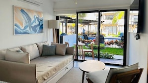 A modern living room with a sofa, a small table, and a ceiling fan. - Ambar Apartments (Mazatlán)