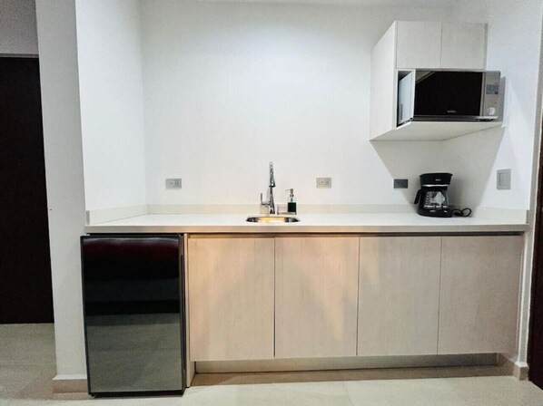 A compact kitchen with a microwave, coffee maker, and a built-in oven. - Ambar Apartments (Mazatlán)
