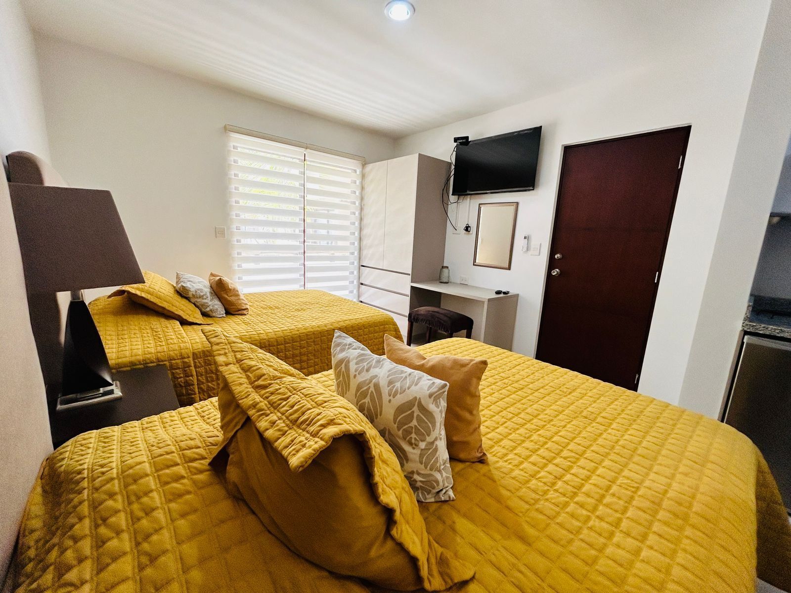 A hotel room with two beds, a desk, a TV, and a wardrobe.