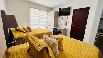 A hotel room with two beds, a desk, a TV, and a wardrobe.