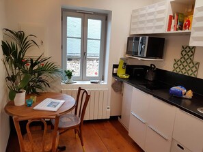 A compact kitchen with a dining area, featuring a window, a microwave, a kettle, and a small potted plant. - Tour Saint Nicolas, in downtown Beaune (Beaune)
