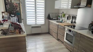 A modern kitchen with wooden cabinets, a built-in oven, and a stainless steel sink.