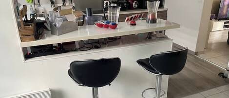 A modern kitchen with white cabinets, a white countertop, and two black bar stools.