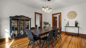 A dining area with a wooden floor, a dark wooden table, and black chairs. There is a glass cabinet with various items on the left. - Vitality Retreat - 1 block from DT/riverfront/shops/bars (Washington)