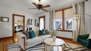 A living room with a white sofa, a round coffee table, and a ceiling fan. - Vitality Retreat - 1 block from DT/riverfront/shops/bars (Washington)