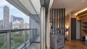Un apartamento moderno con balcón, un sillón gris y vista a la ciudad.