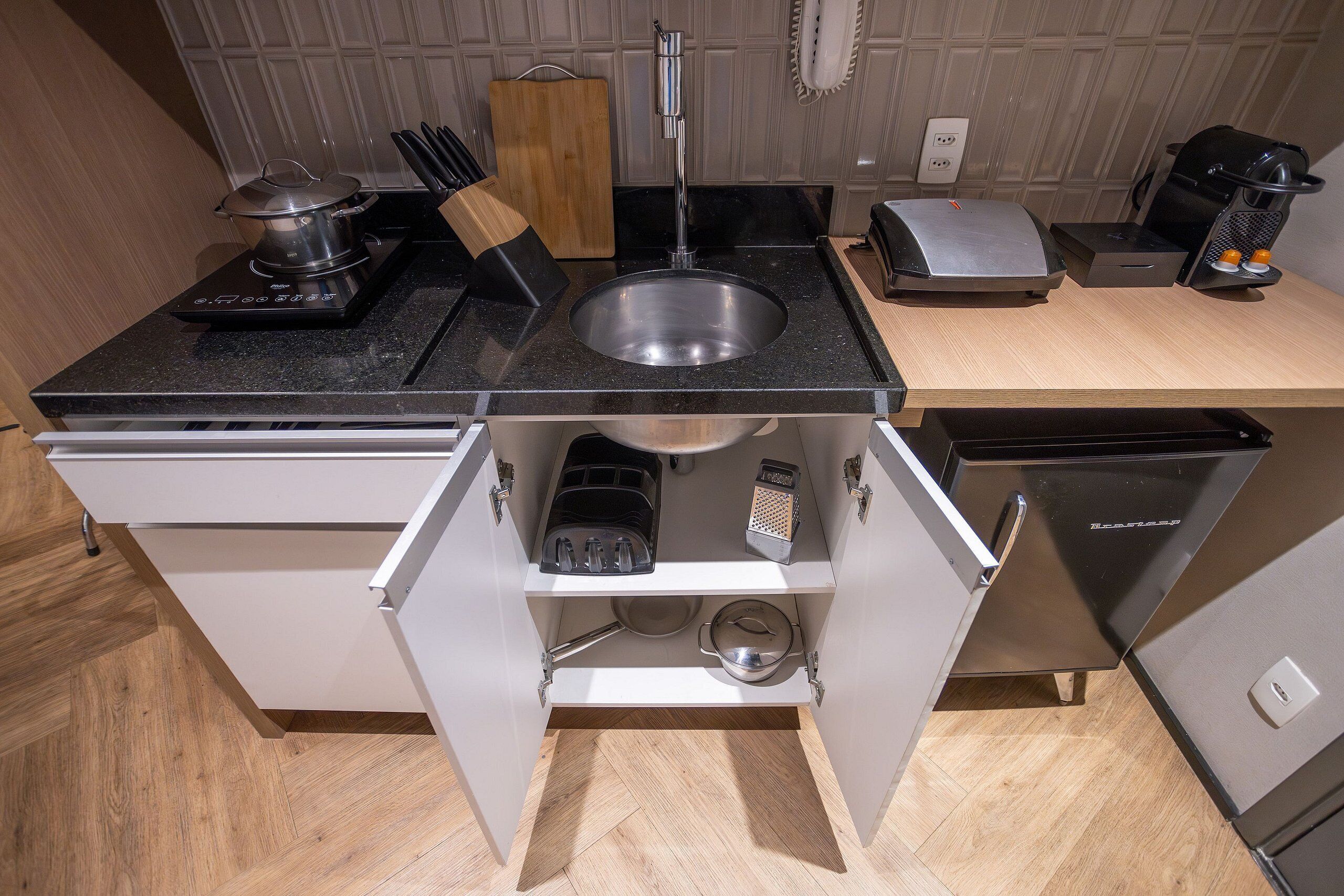 A compact kitchen with a sink, stove, and integrated dishwasher.