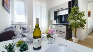 A modern living room with a dining table set for a meal, a wine bottle, and a potted plant. - Bright terrace in Milan (Milano)