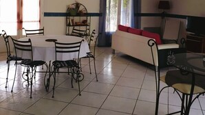 Un salon comprenant un coin repas, un canapé, un téléviseur et un ventilateur de plafond.