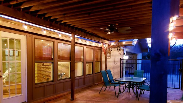 An outdoor patio with brick flooring, wooden pergola, and string lights. - Brooks Retreat: Swimming! Game Room! Staycation! (Richland Hills)