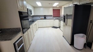A kitchen with white cabinets, stainless steel appliances, and a granite countertop. - Brooks Retreat: Swimming! Game Room! Staycation! (Richland Hills)