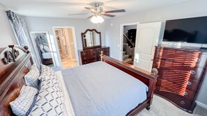 Cozy retreat with a large bed, dresser, and mounted TV.
