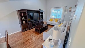 Relax in this stylish living room with a flat-screen TV, comfortable sofa, and natural light pouring in through the window.