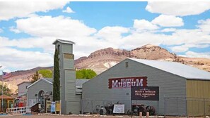 Situated in a desert landscape, the Beaty Museum features a simple, single-story design with a flat roof and a prominent chimney.