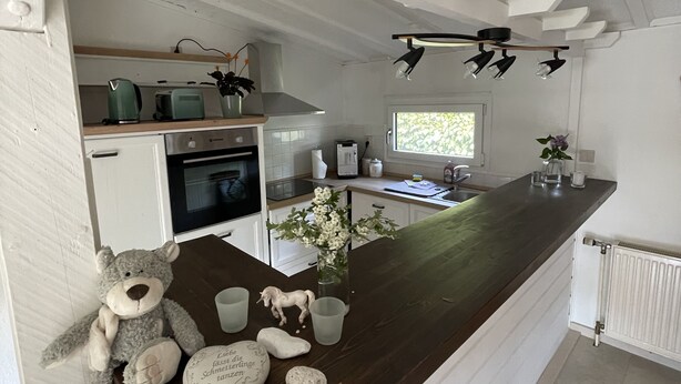 Eine moderne Küche mit dunkler Holz Arbeitsplatte, weißen Schränken und Pendelleuchten.