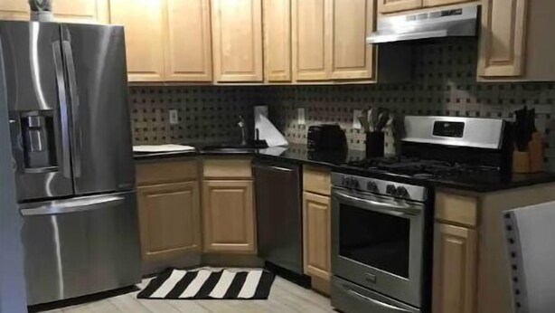 Una cucina con mobili in legno, elettrodomestici in acciaio inossidabile e un tappeto a righe.