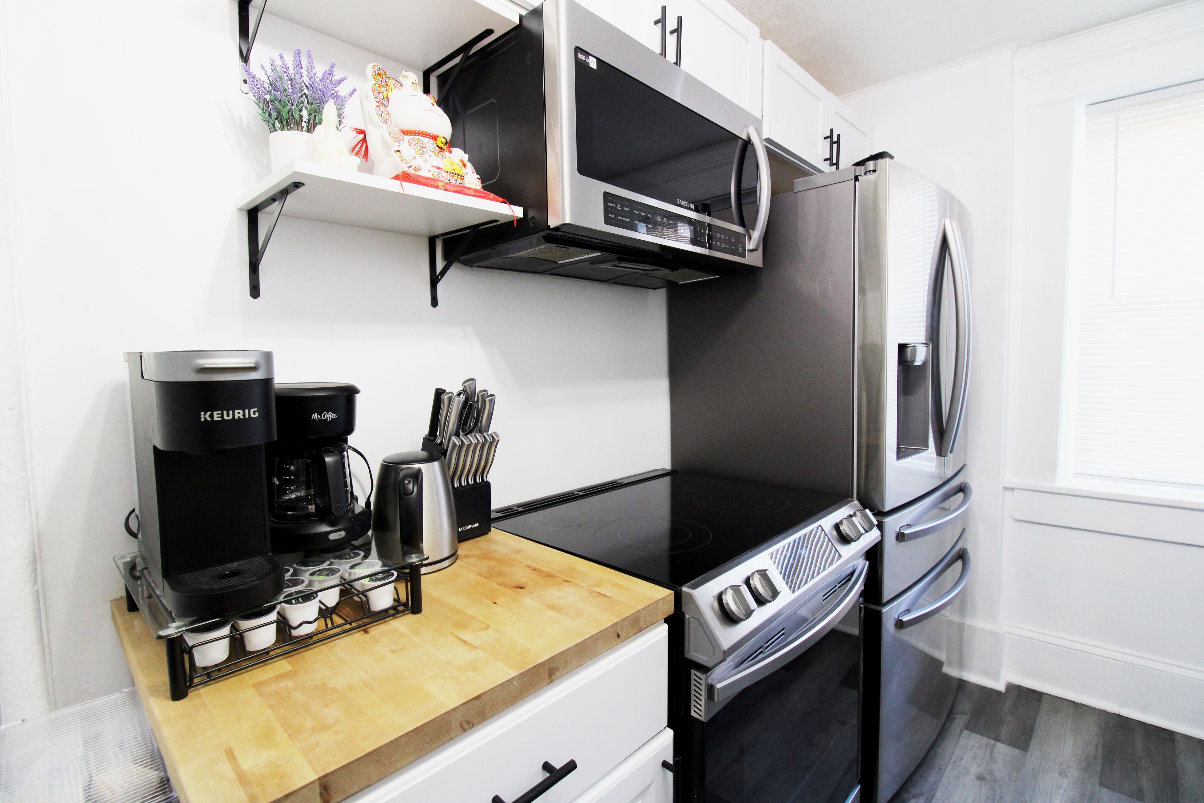 A compact kitchen with a black stove, a microwave, a refrigerator, and a coffee maker.