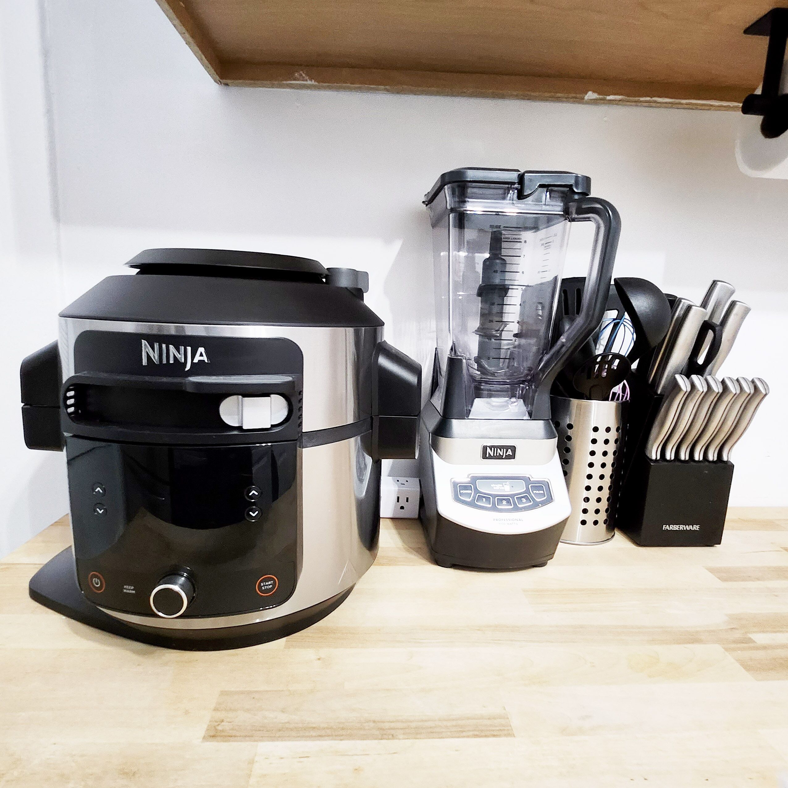 A kitchen with a Ninja coffee maker, a blender, and a knife block.