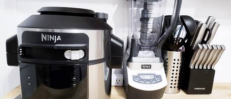 A kitchen with a Ninja coffee maker, a blender, and a knife block.