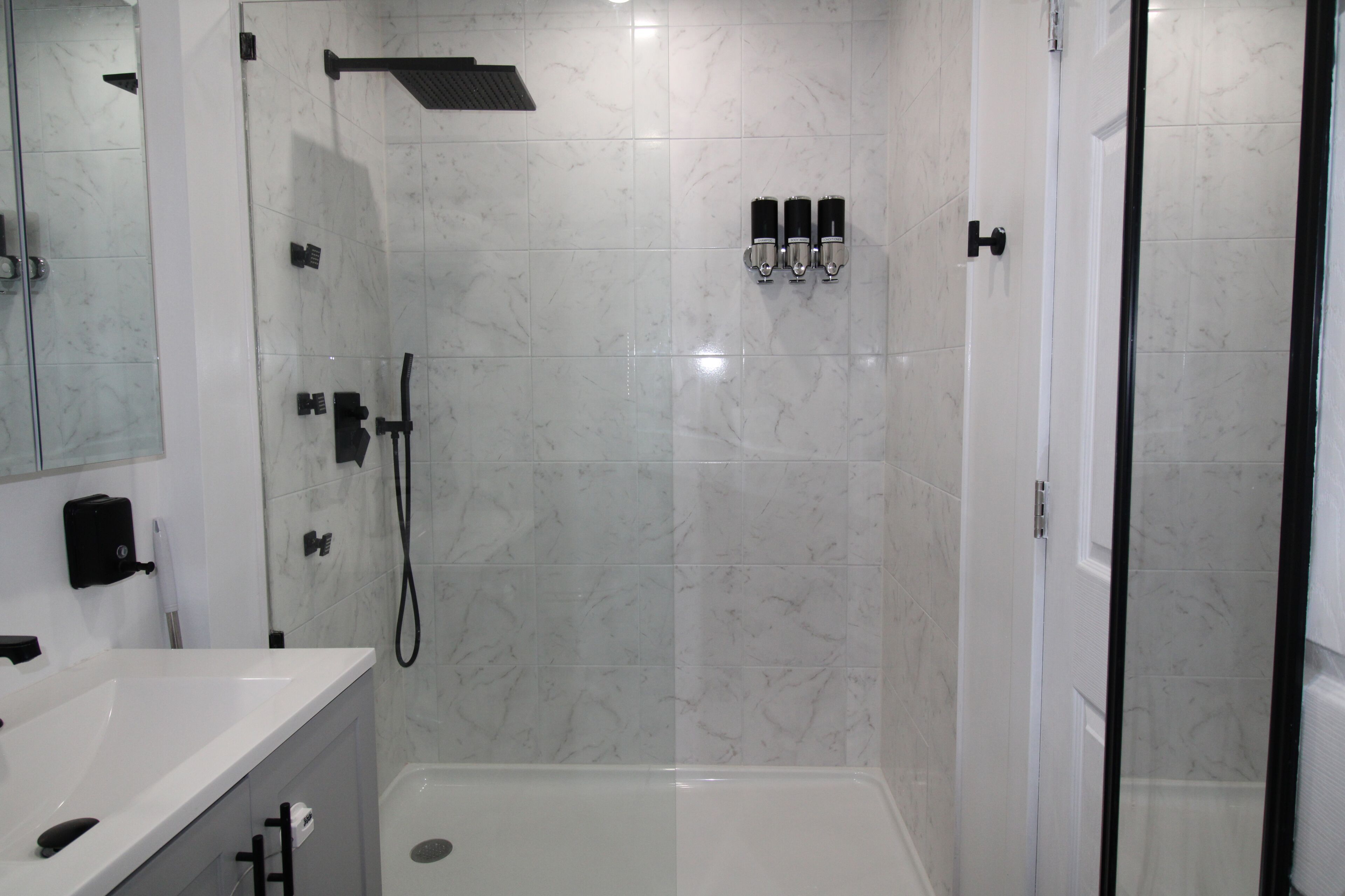 A modern bathroom with a glass-enclosed shower, a white sink, and a mirror.