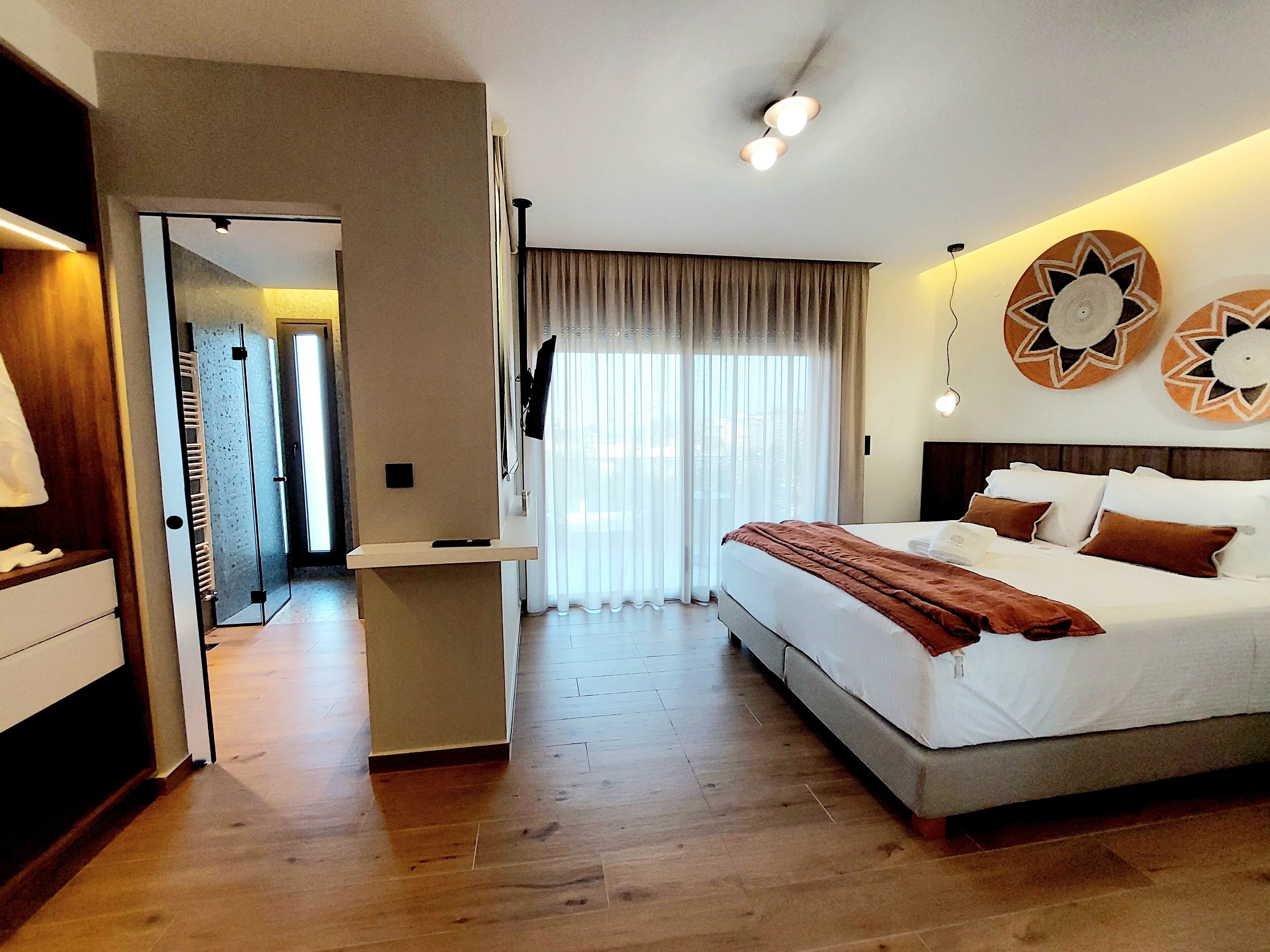 A hotel room with a large bed, a desk, and a view of the outdoors through the window.