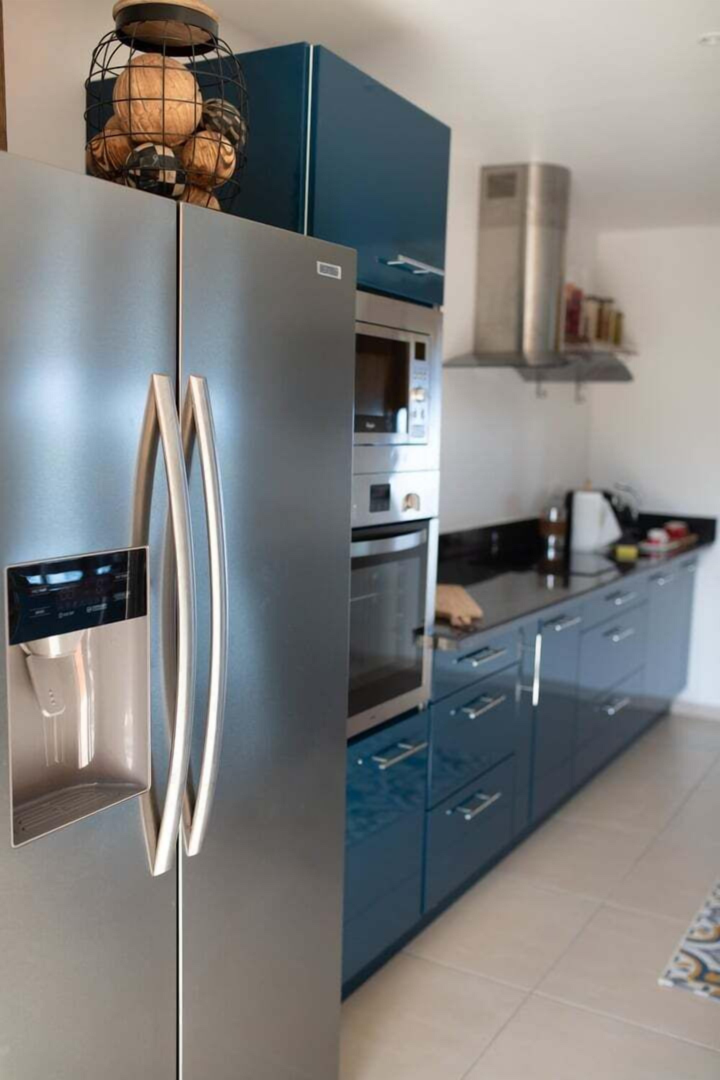 Une cuisine moderne équipée d’un réfrigérateur en acier inoxydable, d’un four encastré et d’un four à micro-ondes.