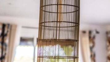 Een hanglamp van bamboe in een kamer met een bed en gordijnen.