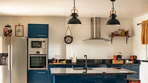 A modern kitchen with a central island, stainless steel appliances, and pendant lighting.