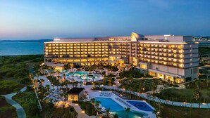 A large, multi-story hotel with a swimming pool complex, surrounded by greenery and overlooking a body of water. - Hilton Okinawa Miyako Island Resort (Miyakojima)