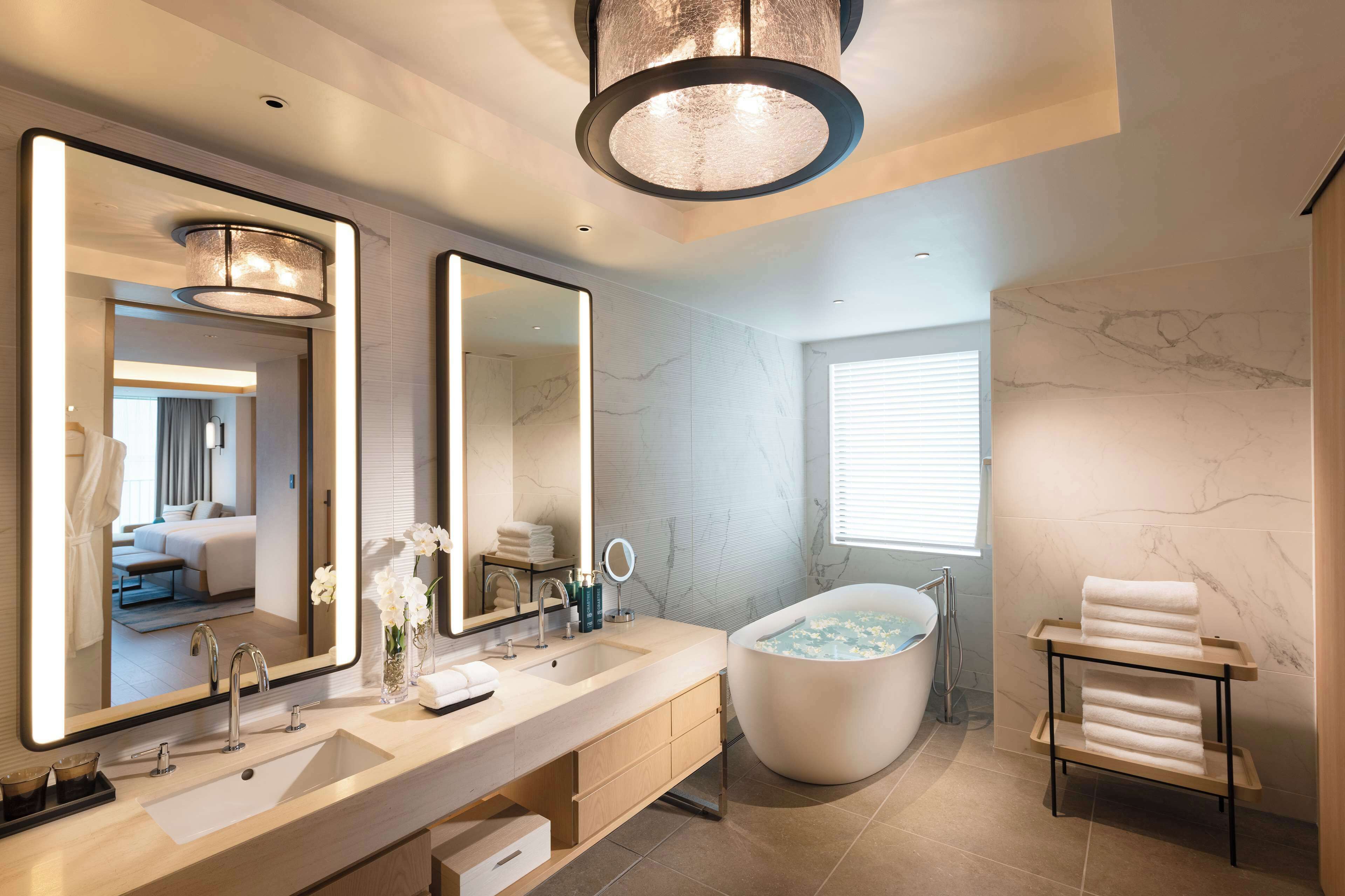 Une salle de bain moderne avec une baignoire sur pieds, un grand miroir et un meuble-lavabo doté d’un évier et d’un porte-serviettes.