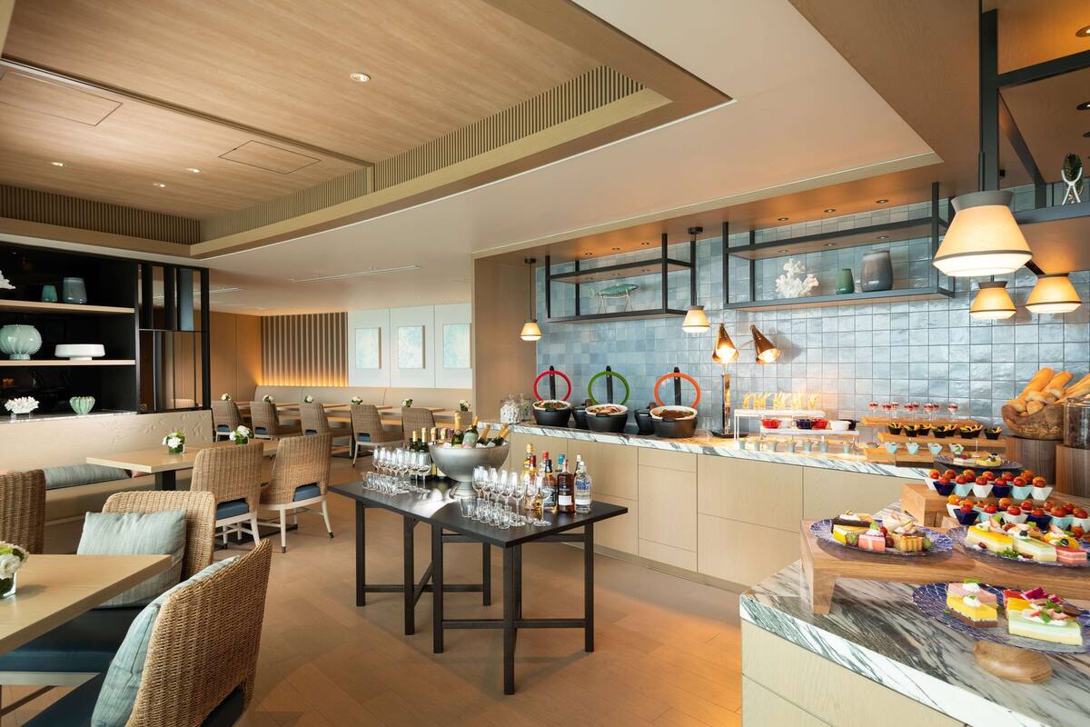 Un moderno vestíbulo de hotel con zonas de estar, un bar y un bufé con diferentes opciones de comida.
