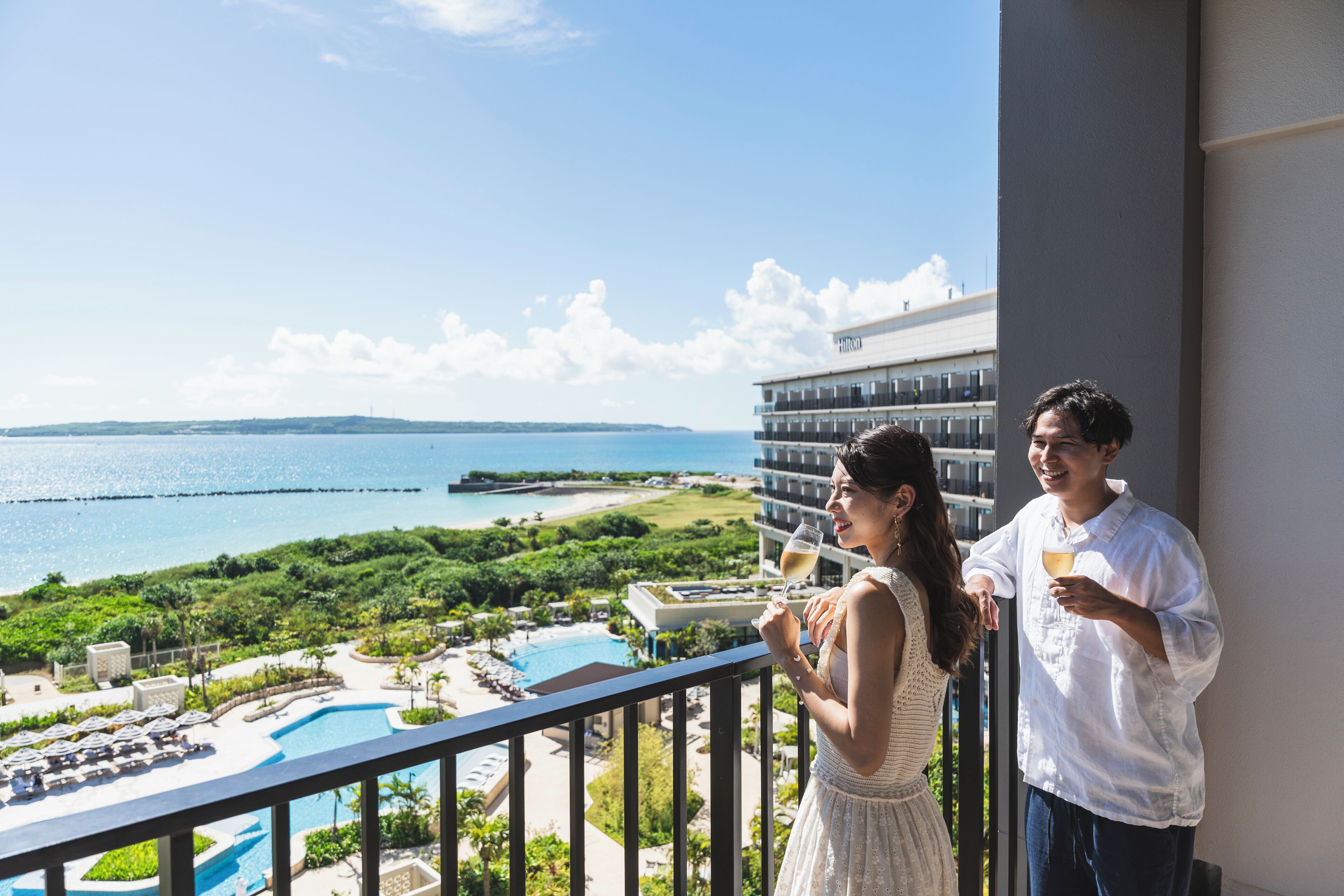 A balcony with a view of a swimming pool and beach.