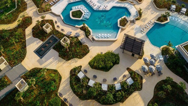 An aerial view of a resort with multiple swimming pools, a beach, and lush greenery. - Hilton Okinawa Miyako Island Resort (Miyakojima)