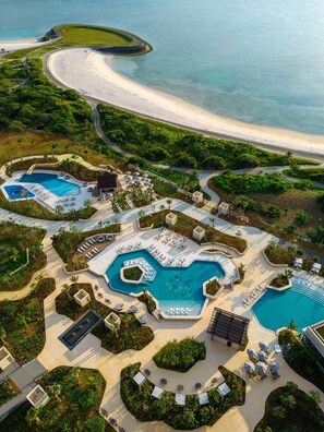 An aerial view of a resort with multiple swimming pools, a beach, and lush greenery. - Hilton Okinawa Miyako Island Resort (Miyakojima)