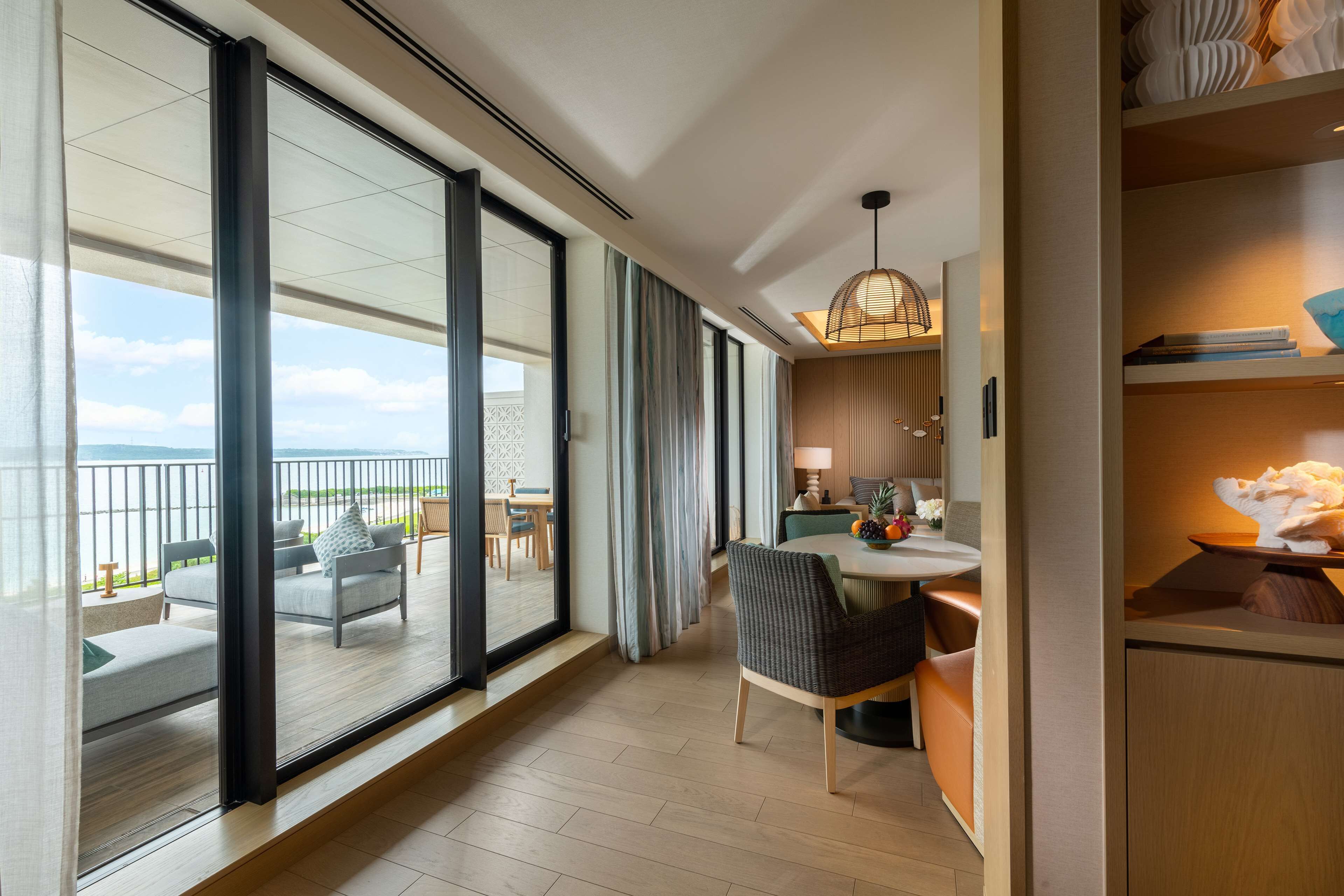 Una habitación de hotel moderna con balcón, comedor y vista al mar.